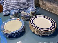 Full view of all plates and teapot set on table showing condition