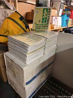 Stacks of Earthbound filler paper packs on a large box in storage space with an orange bag and household items in the background.