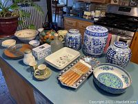 Overview of all ceramic items on kitchen counter including bowls, vases, ginger jars, cups, and trays