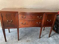 Front view of the wood side bar showing two drawers and two doors with metal handles.