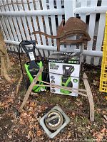 Full lot of items showing antique wood chopper, pressure washer with box, garden shears and sprinkler in outdoor setting.