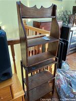 Three-shelf wood shelving unit with decorative top edge showing scratches and wear.
