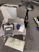 Shows all items including two clipboards, pegboard with insert, pink metal rack, desk lamp, 'Quiet Please' sign, and packing items
