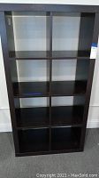 Front view of black wood bookcase showing 8 cubbies in a 4x2 layout.