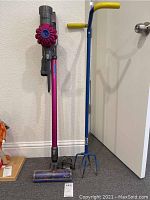 Dyson V6 vacuum and blue-handled weeder side by side