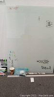 Glass white board showing marker writing and drawings with markers and eraser at base