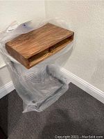 Wooden shelf laptop table covered in protective plastic, showing rectangular top and shelf below