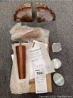 Top view of agate geode bookends, wooden leg wrapped in bubble wrap, crystals and assembly instructions on grey carpet.