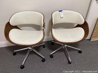 Front view of both chairs showing white seats, wood veneer shells, and chrome bases