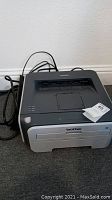 Front view of Brother HL-2170W printer showing the output tray, control panel, and power cord at the back.