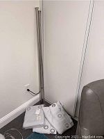 Photo showing silver metal curtain rod standing upright next to folded light gray curtains.