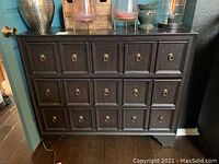 Front view of the black chest of drawers showing all fifteen drawers with metal ring pulls.