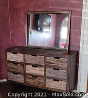 Photo showing the dresser with rustic wood drawers and mirror above, against a dark red wall.