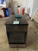 Full view of the Electric Opal ice maker showing black and stainless steel design with glass pieces on top.