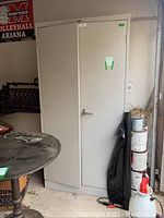 Full view of tall metal cabinet with double doors in a garage setting showing general appearance and condition.