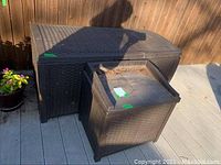 Two brown plastic outdoor storage boxes with rattan-style texture on patio deck near pool.