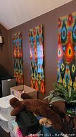 Three multicolored vertical wall art panels mounted on a brown wall.