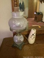 Photo of vintage white etched glass lamp with floral design on the globe and metal ornate base