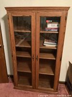 Front view of oak bookshelf showing two glass doors and interior shelves with some books inside.