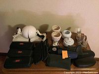 Photo showing porcelain clown bookends holding a white sphere, multiple eyeglass cases around them, some with glasses inside, and figurines on a table.