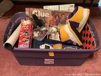 Large purple Sterilite bin filled with various games and a plush Minnesota Vikings house shoe.