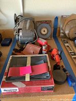 Electric floor sander, sanding discs, Armstrong flooring, and tools on wooden shelves.