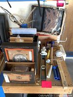 Lot of Harley-Davidson front fender skirts boxes, paint tray, paint roller, hardware parts, spirit level and rolls of tape on wooden table