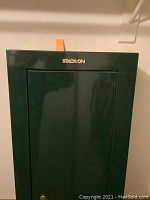 Photo of green Stack-On standing wall safe showing front door with lock and logo.