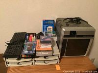 Photo showing the Slide Telex Caramate Machine next to a wired keyboard, paper filer drawers, pens, various discs and software box.
