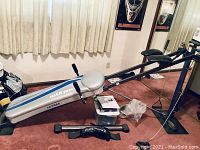 Photo of Total Gym exercise rowing machine with padded seat and handles, positioned near curtain and mirror.