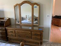 Full view of Broyhill wooden dresser with attached three-panel mirror showing wood grain, glass top, and drawer arrangement.