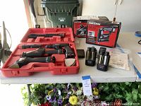 Craftsman cordless tools arranged in red carrying case with two batteries, chargers, and boxes for tools.