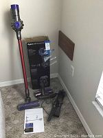 Dyson V6 Absolute assembled with wand, floor head, box and accessories on carpet