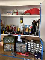 Full view of shelves holding multiple organizer drawers with screws, bolts, spray cans, hand tools, flashlights, and tape rolls