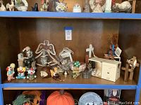 Shelf with assorted home decor including figurines, small pumpkins, wooden decorations, and a decorative angel