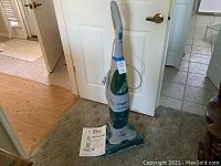 Full view of upright Hoover Floor Mate Spin Scrub cleaner with owner's manual placed on floor.