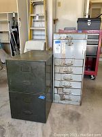Two metal file drawers stackable, dark green with handles, and a light gray metal cabinet with six drawers and a file box on top with latch, showing rust and scratches.