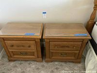 Pair of wooden Broyhill nightstands with two drawers each and clear glass tops, shown side by side on carpeted floor.