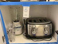 Kitchen cabinet shelf with the toaster, blender, and cocktail shaker arranged side by side