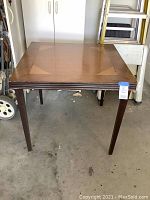 Full view of vintage wooden card table with four legs, showing overall condition and design.