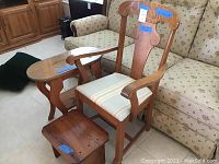 Photo showing the wooden armchair, glass topped oval side table, and handcrafted wooden footstool arranged together in a room.