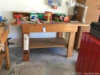 Full view of wooden garage work bench showing structure, shelf, and attached accessories including vice and can crusher.