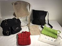 Six small purses arranged on a white surface showing all colors, materials, and styles for clear visual of variety in the lot.