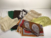 Seven vintage scarves displayed together showing variety of colors including green, brown, black/white, cream, mustard yellow, coral, and lime, various textures and sizes visible.