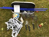 Photo showing all items in the kit set on grass including net, rackets, shuttlecocks, volleyball, and carrying case