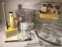 Multiple kitchen helper items including rice steamer, glass bakeware, electric cutter, and chopper in box.