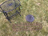 Black metal garden table, rustic antique plant stand, and sundial displayed together on grass, showing size and relative scale.