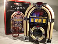 Crosley jukebox CD player with original box and vintage McDonalds Coca Cola glass in front.