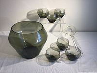 Full set of punchbowl, six glasses, and clear plastic ladle displayed together on white surface