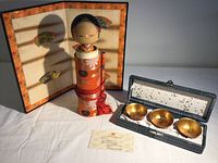 Full lot showing Kokeshi doll, backdrop screen, set of three gold bowls in box, and identification card